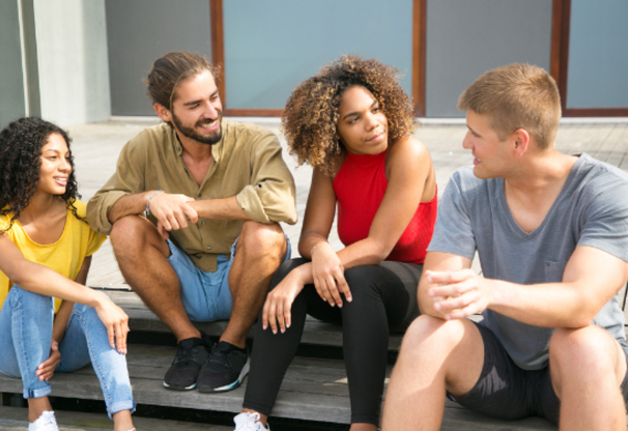 Vier personen zitten samen op een trap en zijn met elkaar in gesprek