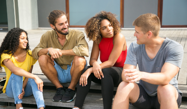 Vier personen zitten samen op een trap en zijn met elkaar in gesprek