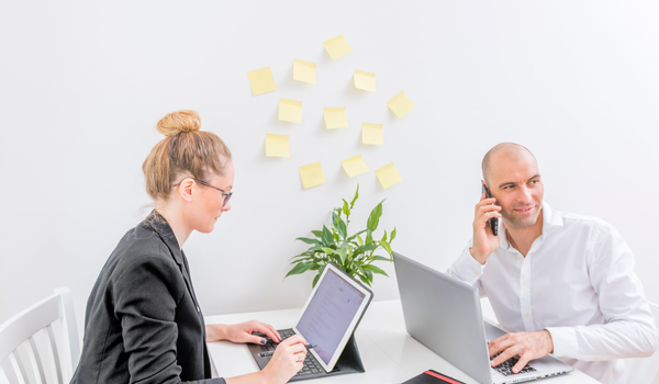 Twee personen werken aan laptops aan een bureau