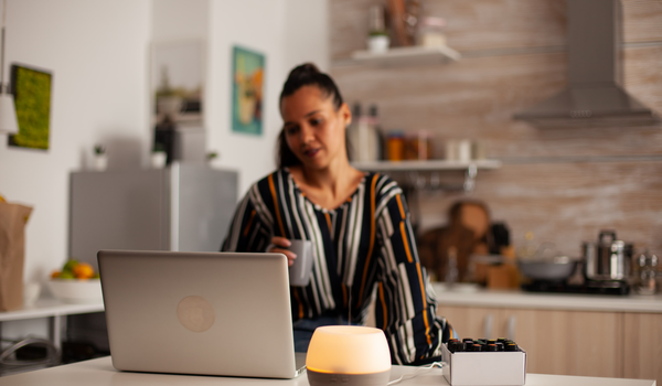 Vrouw werkt aan haar laptop aan een tafel in de keuken