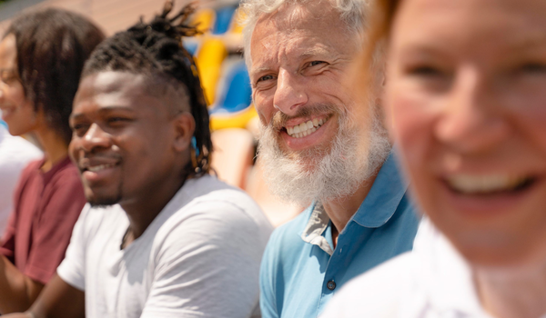 Groep personen zit naast elkaar buiten op een tribune
